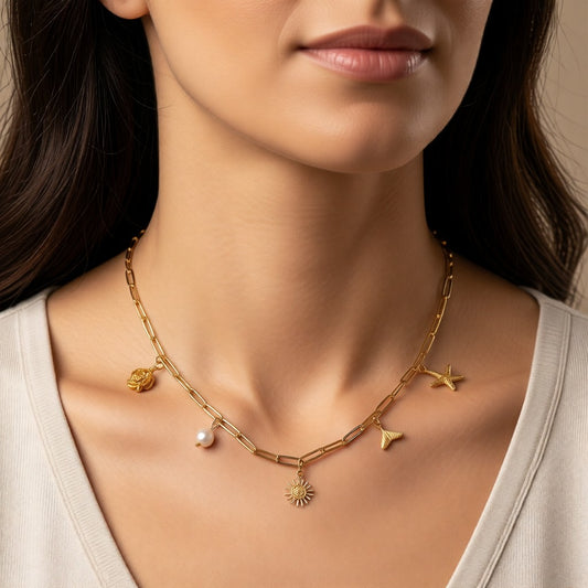 Aramat Jewels gold-tone stainless steel multi charm necklace with paperclip chain, featuring a pearl, sun, starfish, and shell charms.