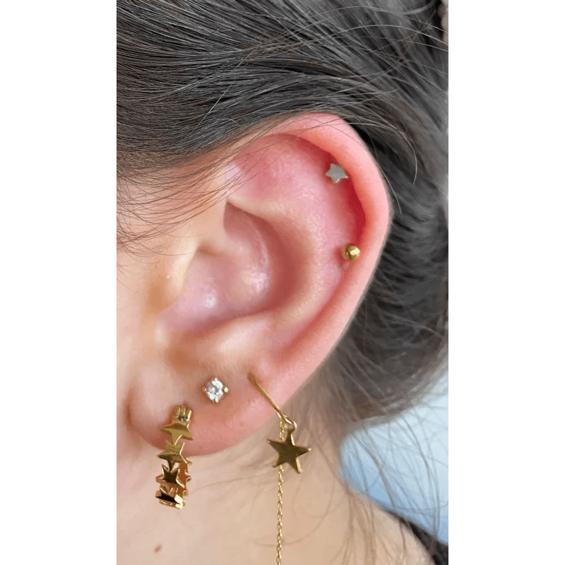 Een vrouw draagt een paar gouden sterren oorboeien