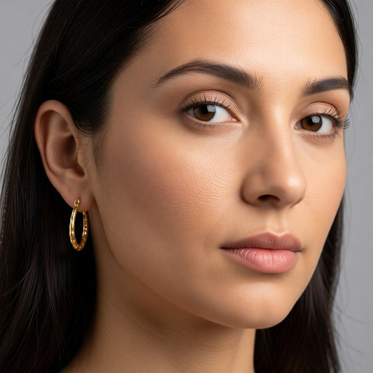 Aramat Jewels gold-coloured stainless steel hoop earrings with a bone-structure texture, 25mm diameter.