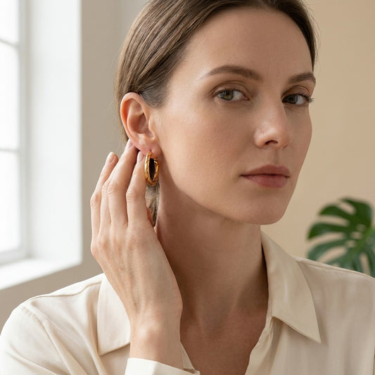 Aramat Jewels gold-coloured stainless steel hoop earrings with a twisted rope motif, 25x3.5mm, worn by a woman.