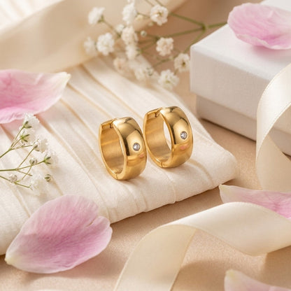 Aramat Jewels gold-tone stainless steel huggie hoop earrings with a central cubic zirconia stone.