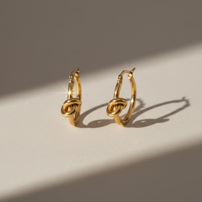 Aramat Jewels gold-tone stainless steel hoop earrings with a knot detail, 25mm diameter.