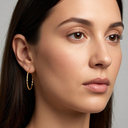 Aramat Jewels gold-colored twisted stainless steel hoop earrings, 30mm diameter, with a link motif and hinge closure.