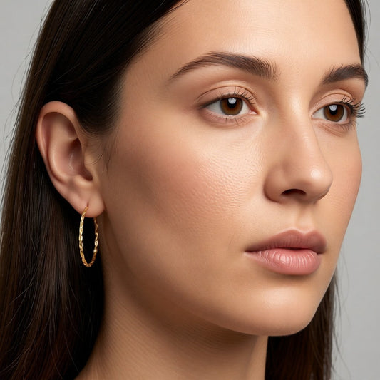 Aramat Jewels gold-colored twisted stainless steel hoop earrings, 30mm diameter, with a link motif and hinge closure.