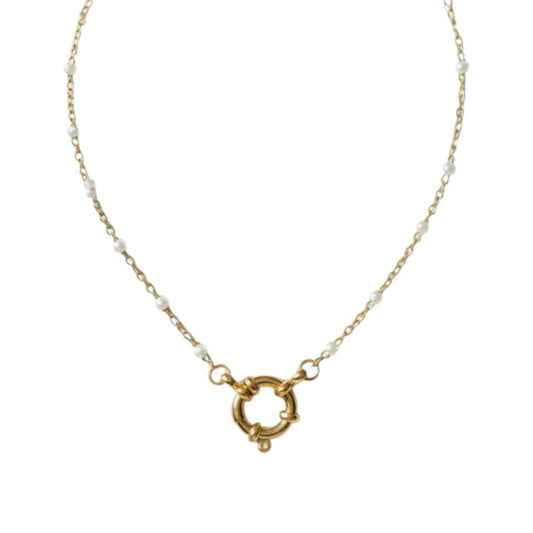 Aramat Jewels gold-tone stainless steel necklace with white enamel beads and a circular clasp, displayed on a branch.