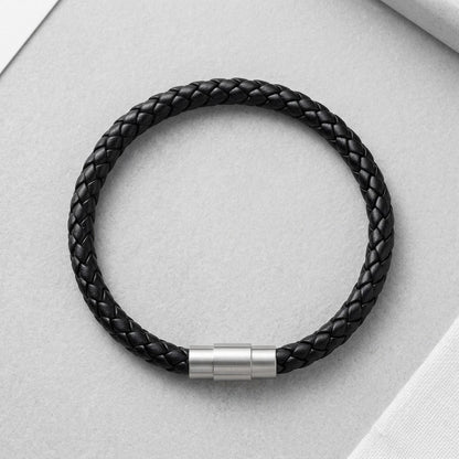 Aramat Jewels zwarte gevlochten leren herenarmband met een zilverkleurige RVS magneetsluiting op een grijze ondergrond.