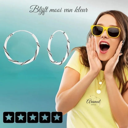 Aramat Jewels 20mm oxidised silver Bali hoop earrings with twisted detail. Model wears yellow shirt and sunglasses.