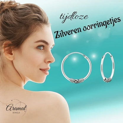 Aramat Jewels 18mm oxidized silver Bali hoop earrings with intricate detailing, worn by a woman.