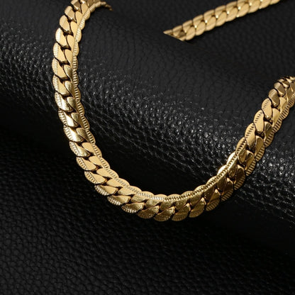 Aramat Jewels platte gourmet ketting van 6mm breed goudkleurig staal met een unieke bewerkte rand op zwarte ondergrond