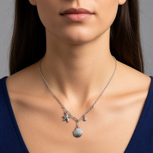 Aramat Jewels silver-tone necklace with seashell, starfish, and cubic zirconia charms on a woman wearing a blue top.