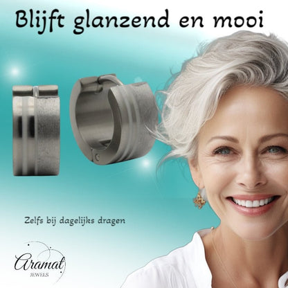 Aramat Jewels silver-tone stainless steel hoop earrings with sandblasted and polished stripes, 13mm. Model with grey hair smiles.