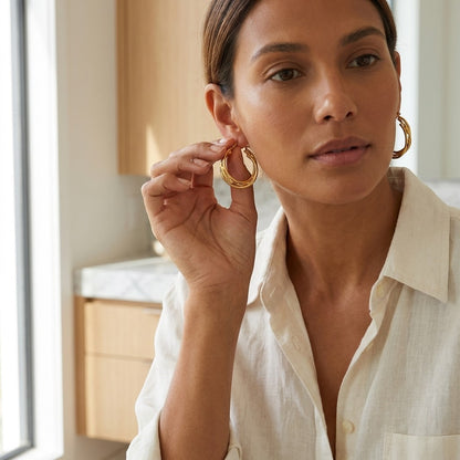 Aramat Jewels triple gold hoop earrings with a twisted detail, 30x7mm, worn by a woman.