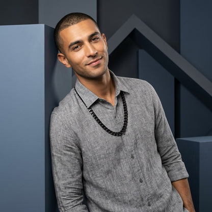 Man draagt een stoere zwarte Aramat Jewels gourmet schakelketting van roestvrij staal in een moderne studio setting.