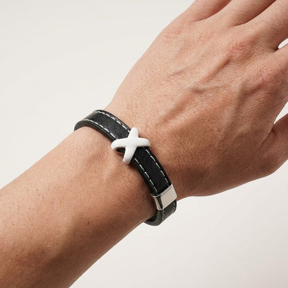 Aramat Jewels zwarte leren herenarmband met wit stiksel en een opvallend kruisje om de pols.