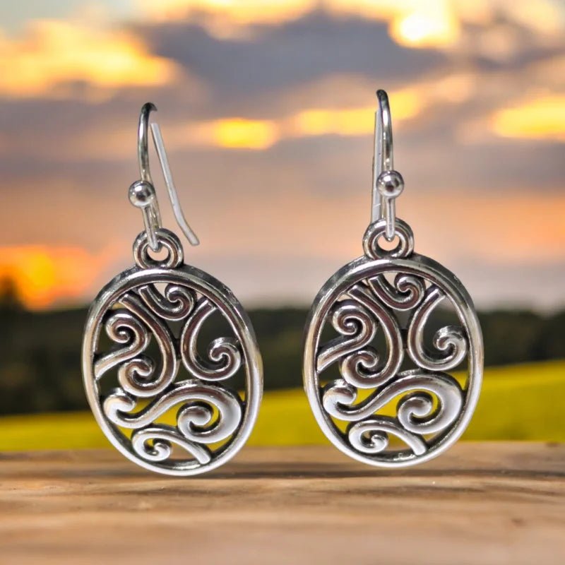 Paar zilveren oorbellen met ovaalvormige hangers met wervelende Keltisch geïnspireerde ontwerpen.