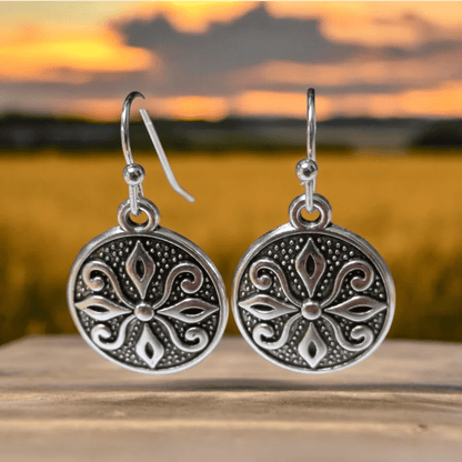 Paar sierlijke zilveren ronde oorbellen met ingewikkelde bloemmotieven.
