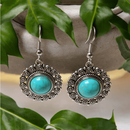 Paar sierlijke zilveren oorbellen met turquoise edelstenen in een cirkelvormig ontwerp.