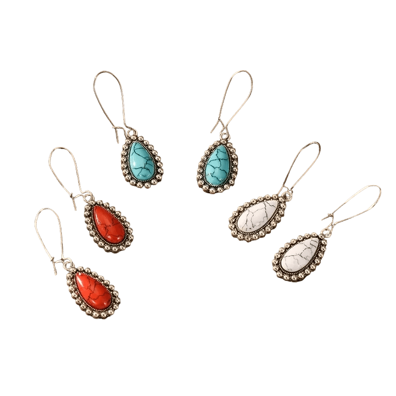 Drie paar druppelvormige oorbellen met edelstenen in turquoise, rode en witte kleuren, gezet in een sierlijk metalen montuur.