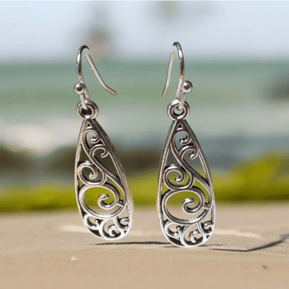 Paar zilveren druppelvormige oorbellen met ingewikkelde krulmotieven.