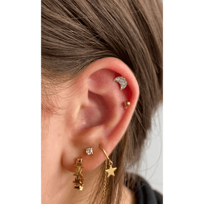 Een vrouw met een gouden ster als oorpiercing