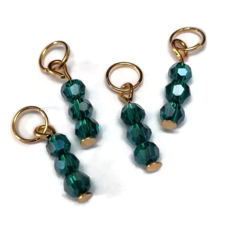 Drie smaragdgroene kristallen kralen hangen aan vergulde haakjes