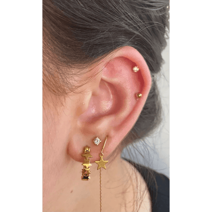 Een vrouw draagt een gouden oorketting met een ster en maan ontwerp