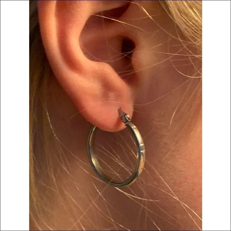 Een vrouw draagt een zilveren hoepel oorbel