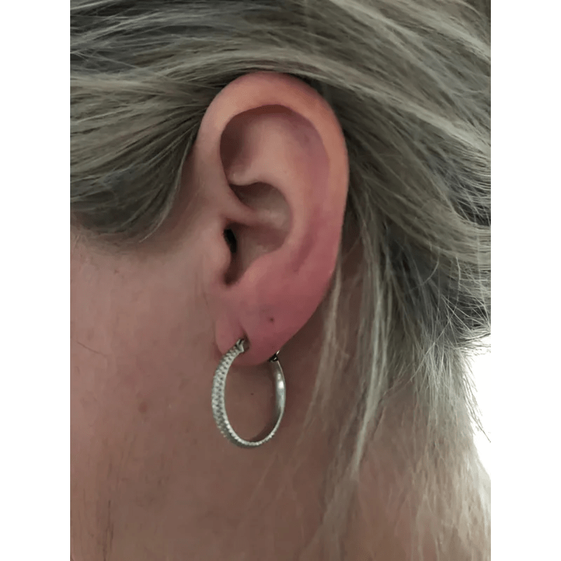 Een vrouw met grijs haar die een zilveren oorbel draagt