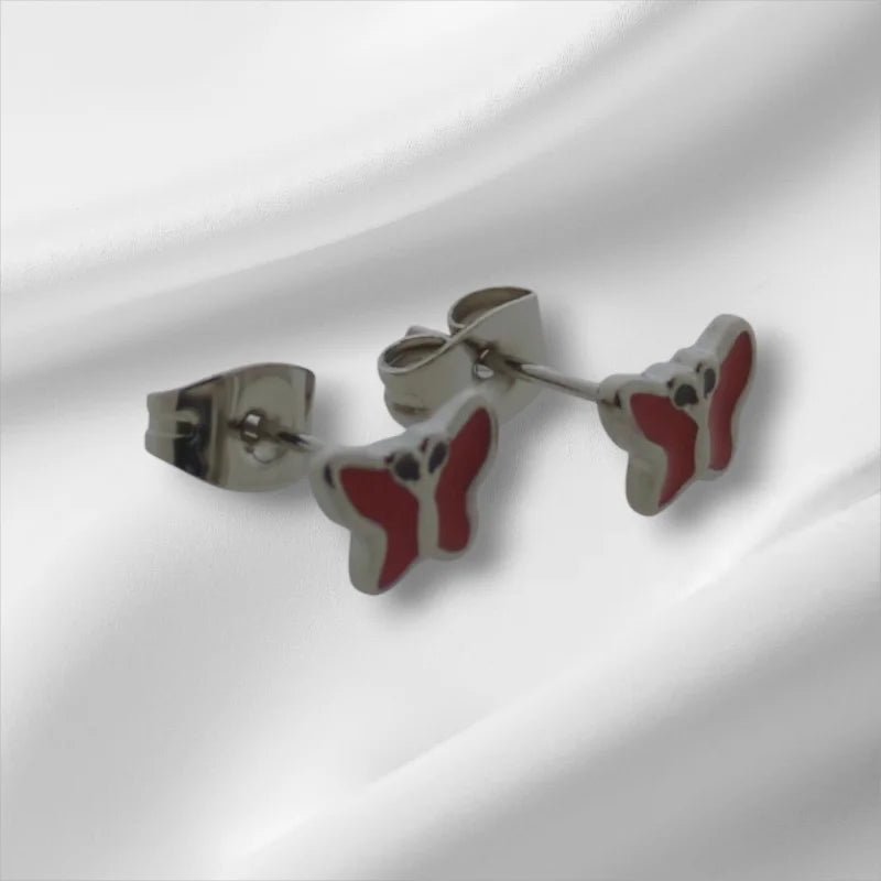 Rode en zilveren oorbellen in de vorm van een vlinder.