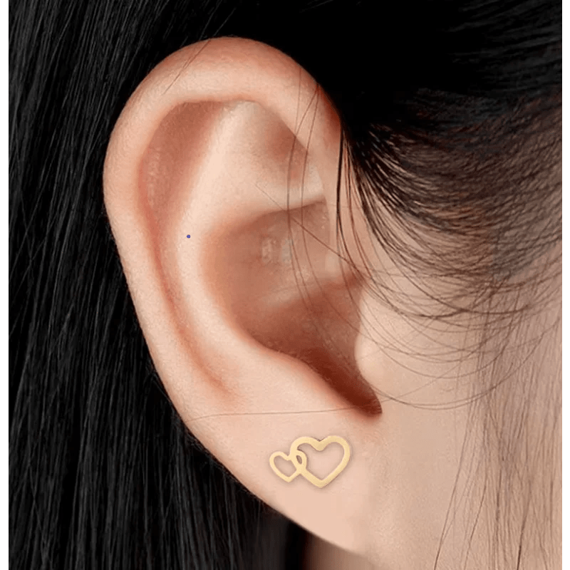 Gouden dubbele hart oorbel gedragen in een oorlel.