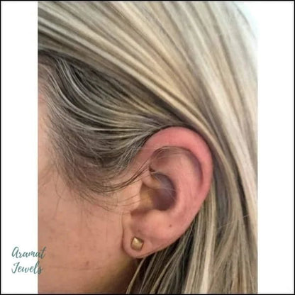 Een vrouw met blond haar en een gouden oorpiercing