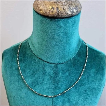 Een close-up van een halsketting op een paspop met een blauwe achtergrond